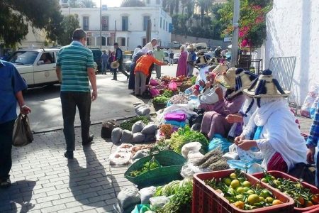 Mercado callejero en Tánger con vendedoras de verduras y frutas con sombreros de paja tradicionales