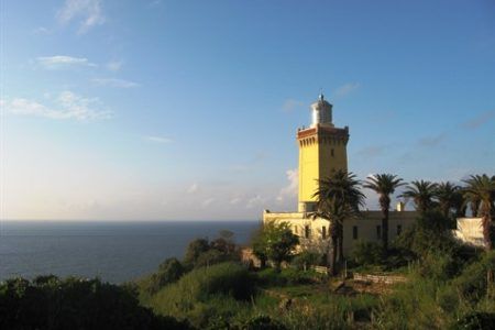 Faro de Cap Spartel en Tánger al atardecer con palmeras y el estrecho de Gibraltar al fondo