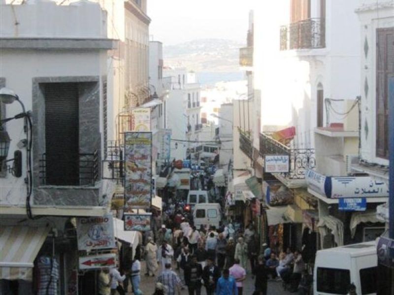 Calle del centro histórico de Tánger abarrotada de viajeros y locales con carteles en árabe
