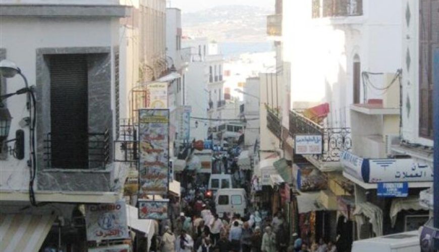 Calle del centro histórico de Tánger abarrotada de viajeros y locales con carteles en árabe