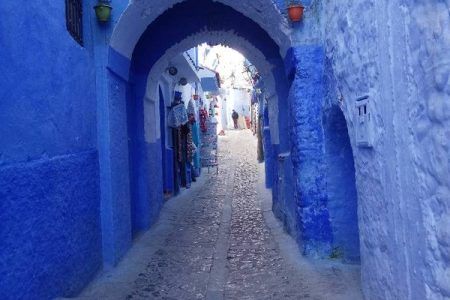 Callejón azul empedrado con arco de entrada en la medina de Chefchaouen, emblema de la ciudad azul marroquí