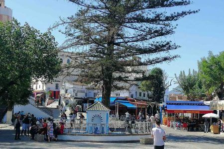 Plaza central de Chefchaouen con fuente ornamental, café al aire libre y minarete al fondo