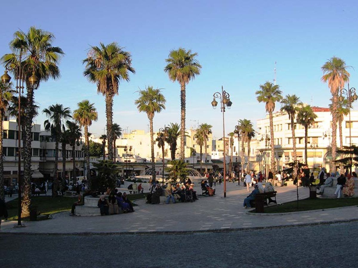 Plaza de Tánger con palmeras, viajeros y locales sentados disfrutando al atardecer