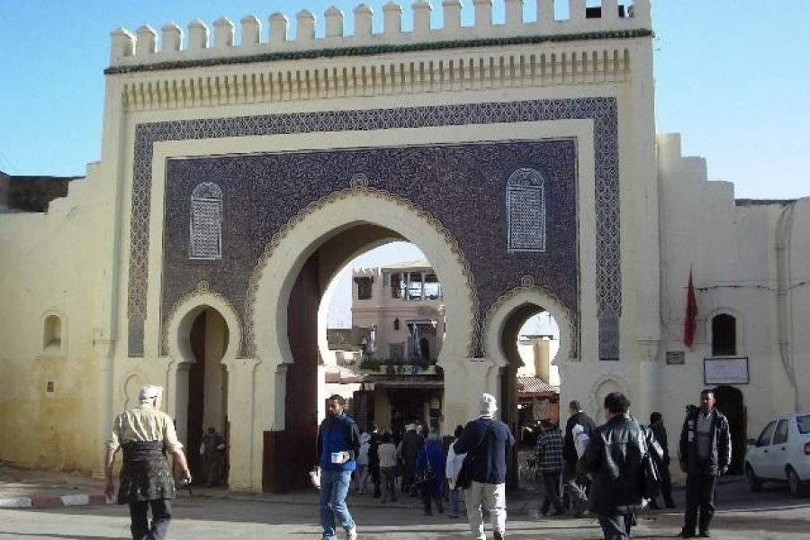 Bab Bou Jeloud, la puerta azul monumental de la medina de Fez, con viajeros paseando ante sus arcos decorados