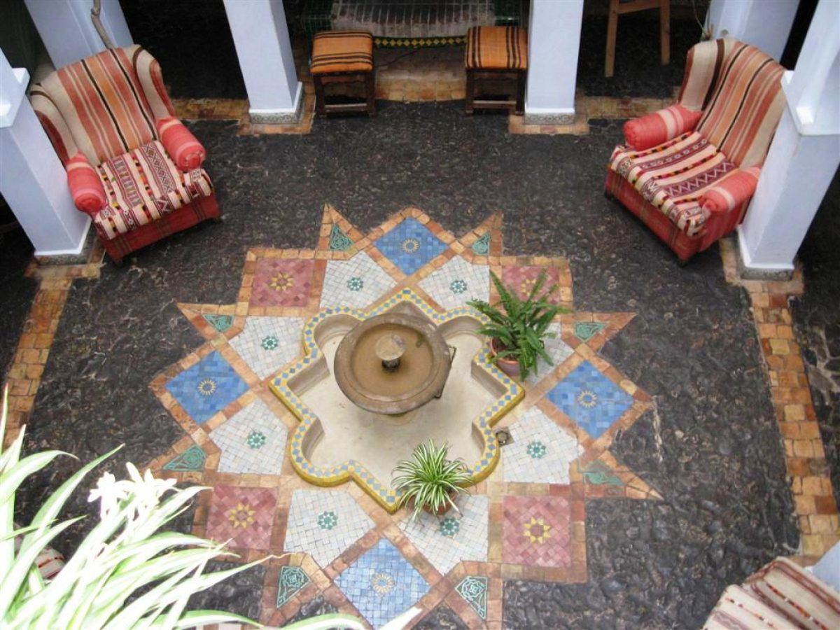 Patio central de la Casa Hassan en Chefchaouen visto desde arriba, con fuente de mosaico y mobiliario tradicional marroquí