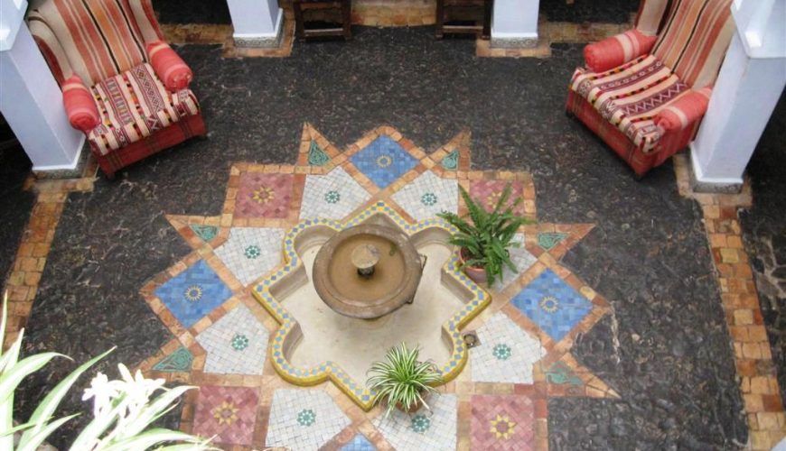 Patio central de la Casa Hassan en Chefchaouen visto desde arriba, con fuente de mosaico y mobiliario tradicional marroquí