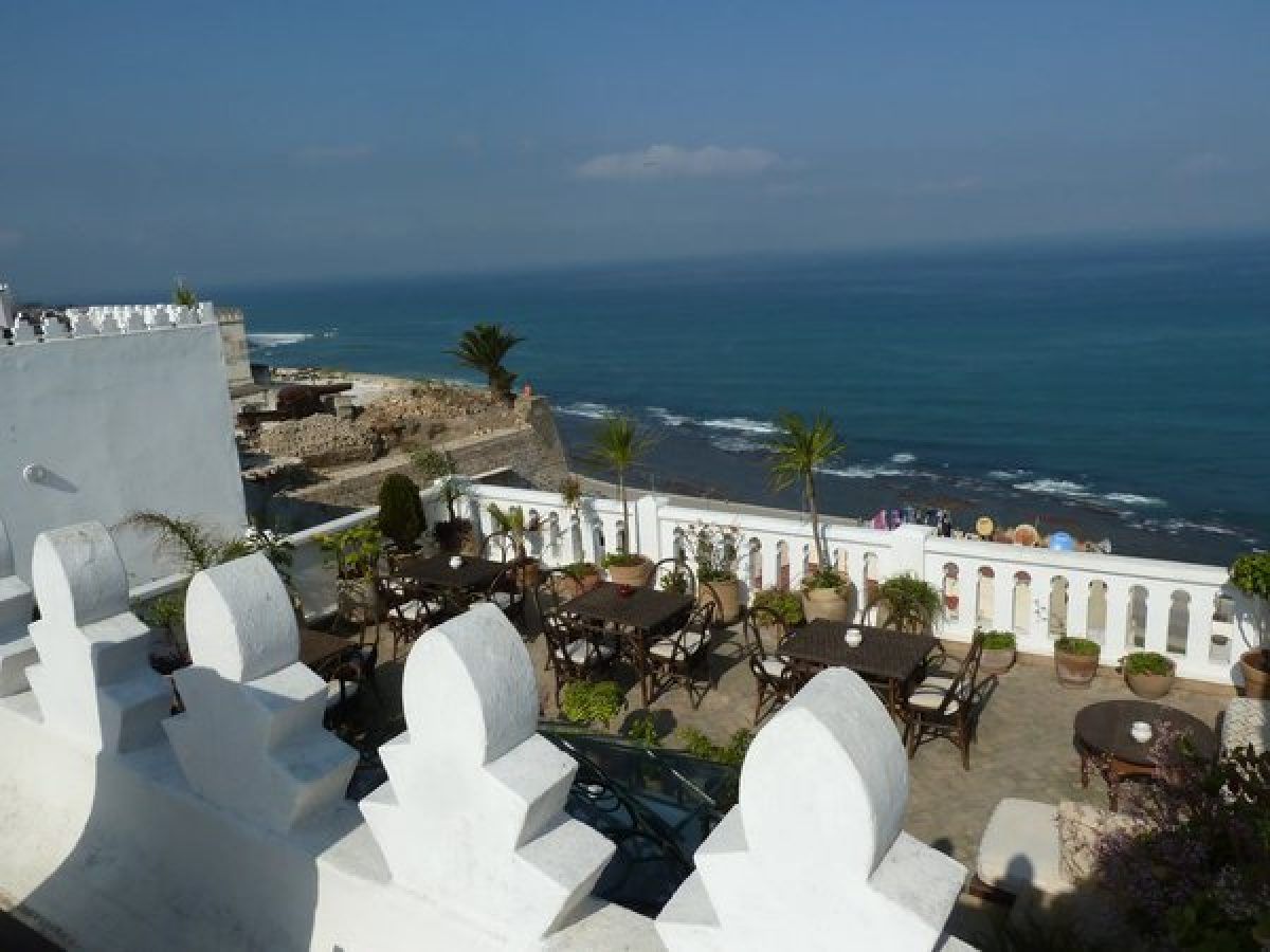 Terraza del hotel boutique La Tangerina en Tánger con vistas al Estrecho de Gibraltar y mesas de restaurante junto a la muralla blanca