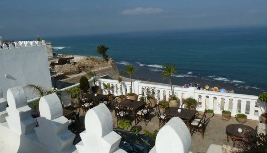 Terraza del hotel boutique La Tangerina en Tánger con vistas al Estrecho de Gibraltar y mesas de restaurante junto a la muralla blanca