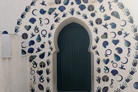 Arco decorado con mosaicos artesanales de conchas, manos y motivos marinos en Asilah