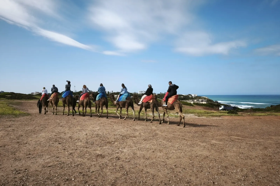 Caravana de camellos con turistas en la costa de Tánger