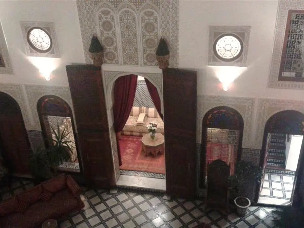 Salón con cortinas rojas visto desde la galería superior – Riad La Perle de la Medina