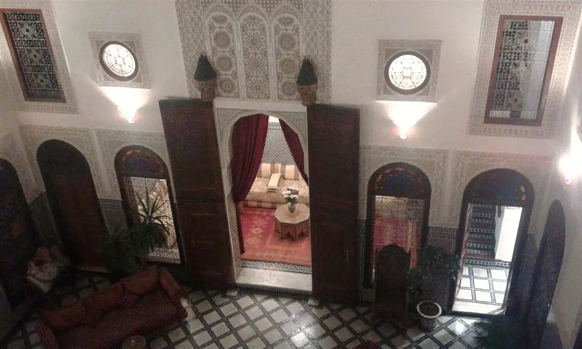 Salón con cortinas rojas visto desde la galería superior – Riad La Perle de la Medina
