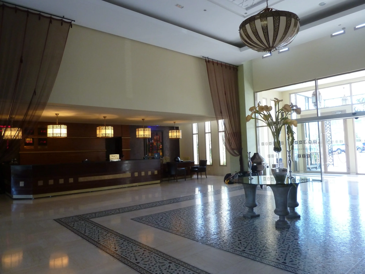 Recepción y lobby del Hotel Palais Medina Fez con mostrador de madera y lámparas colgantes