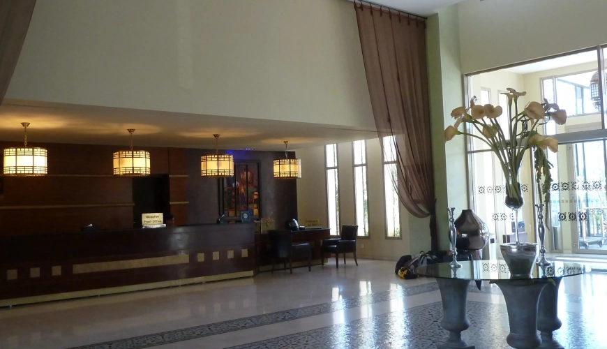Recepción y lobby del Hotel Palais Medina Fez con mostrador de madera y lámparas colgantes