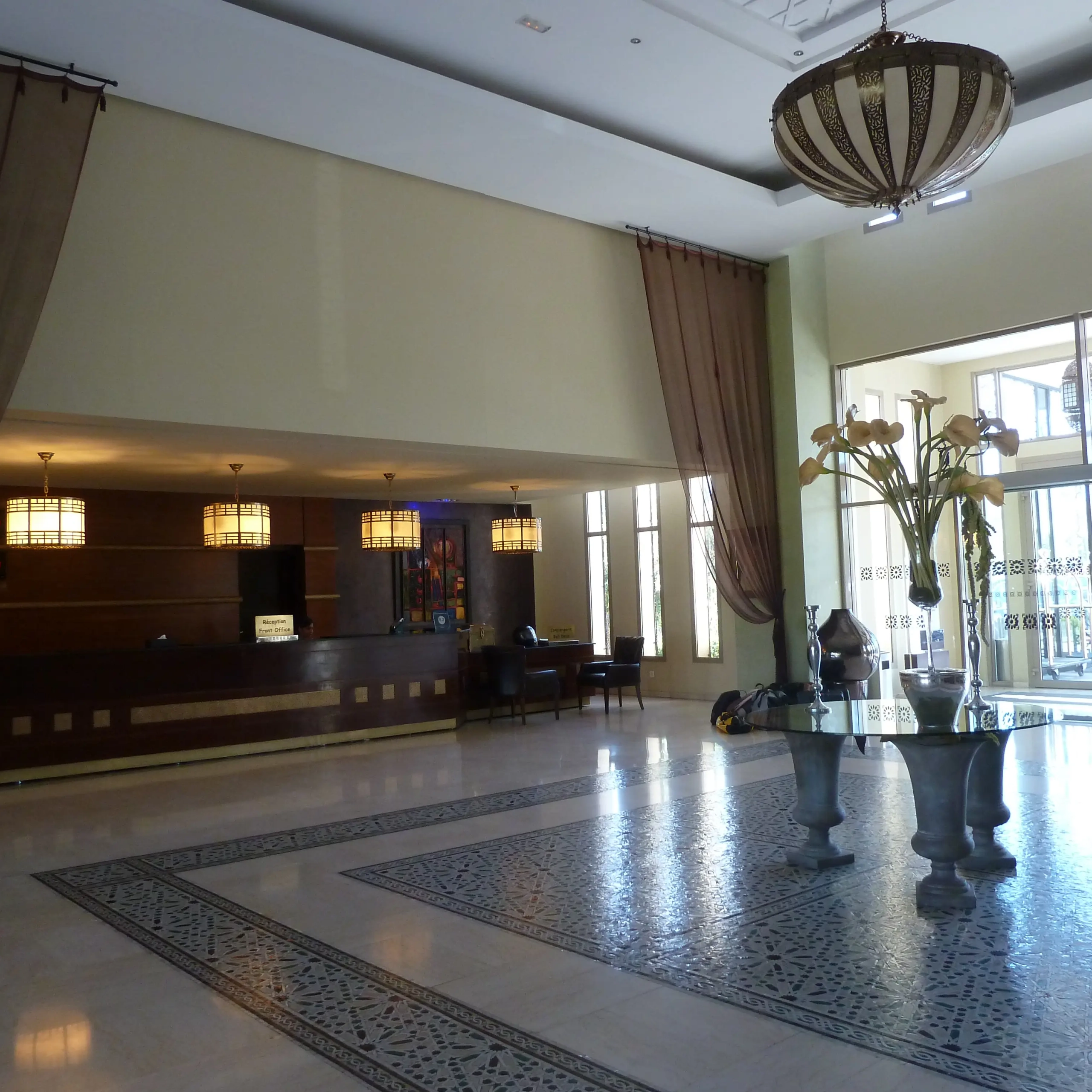 Recepción y lobby del Hotel Palais Medina Fez con mostrador de madera y lámparas colgantes